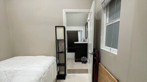 Une chambre à coucher comprenant un lit, une armoire, une fenêtre et un appareil de climatisation.
