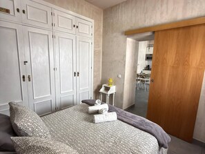 Ein Schlafzimmer mit einem großen Bett, einem Kleiderschrank und Blick zur Küche.