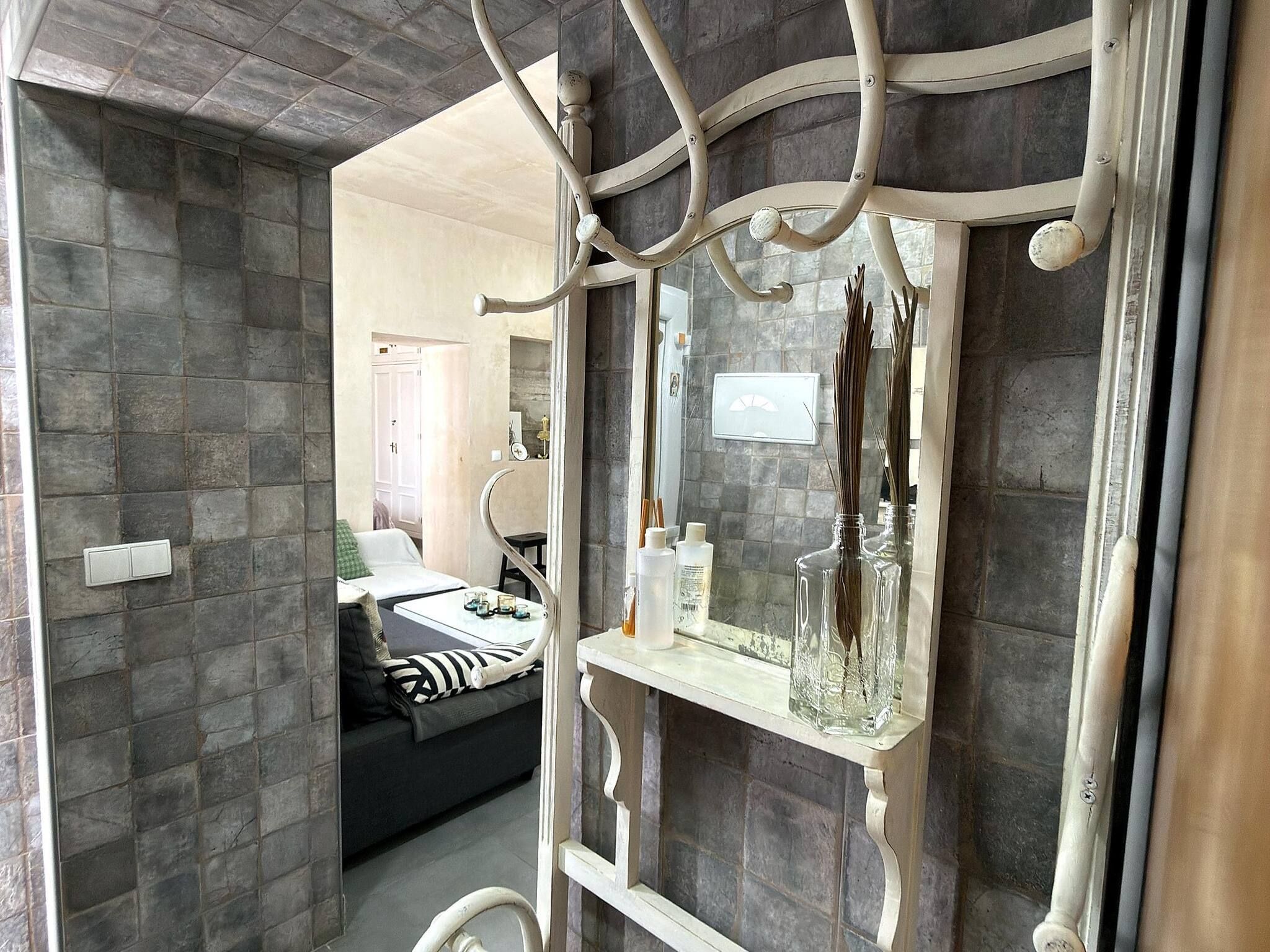 A bathroom with a stone wall, a white vanity with a mirror, and a shower area.