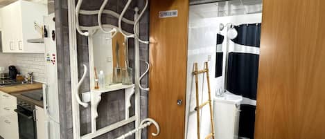Una cocina con un refrigerador blanco, una estufa y un lavamanos. Hay una puerta de madera con un letrero encima.