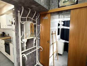 A kitchen with a white refrigerator, a stove, and a sink. There is a wooden door with a sign above it. - Novo home by Staycare (Rota)