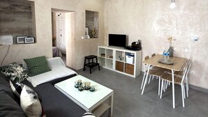 Una sala de estar moderna con sofá, mesa de centro, televisor y un comedor con sillas y mesa.