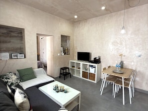 Un salon moderne comprenant un canapé, une table basse, un téléviseur et un coin repas avec des chaises et une table.
