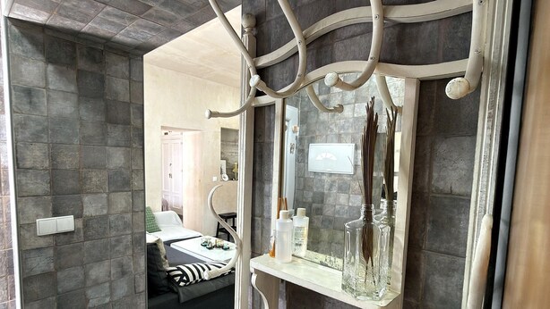 Un baño con pared de piedra, un espejo y un tocador blanco con un florero de vidrio.