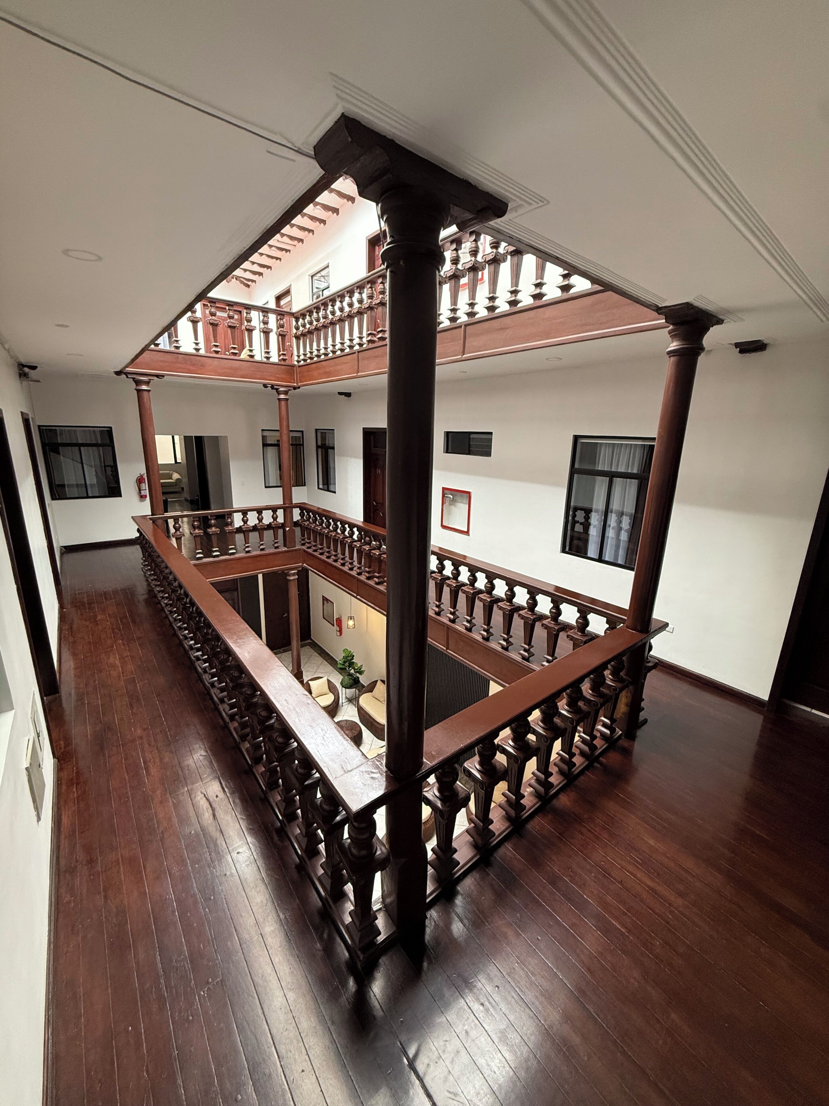 A multi-level wooden balcony with railings, a staircase, and a view of the interior.