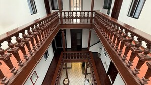 A multi-level interior with a central staircase, wooden railings, and a tiled floor. - Hotel NASS del Sur (Cuenca)