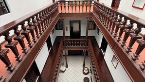 A multi-level interior with a central open space, wooden railings, and a tiled floor. - Hotel NASS del Sur (Cuenca)