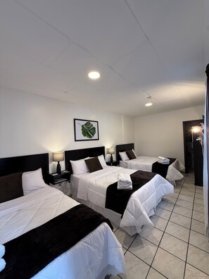 A hotel room with three beds, a ceiling fan, a framed plant, and a tiled floor. - Hotel NASS del Sur (Cuenca)