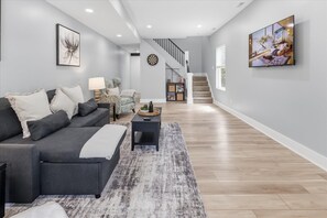 A modern living room with a sofa, a coffee table, and a staircase leading to another level. - All New 3 Story House near Downtown Indy (Indianapolis)