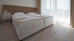 Hotellihuone, jossa on suuri sänky, kaksi yöpöytää, sängynpääty ja näkymä ulos.
