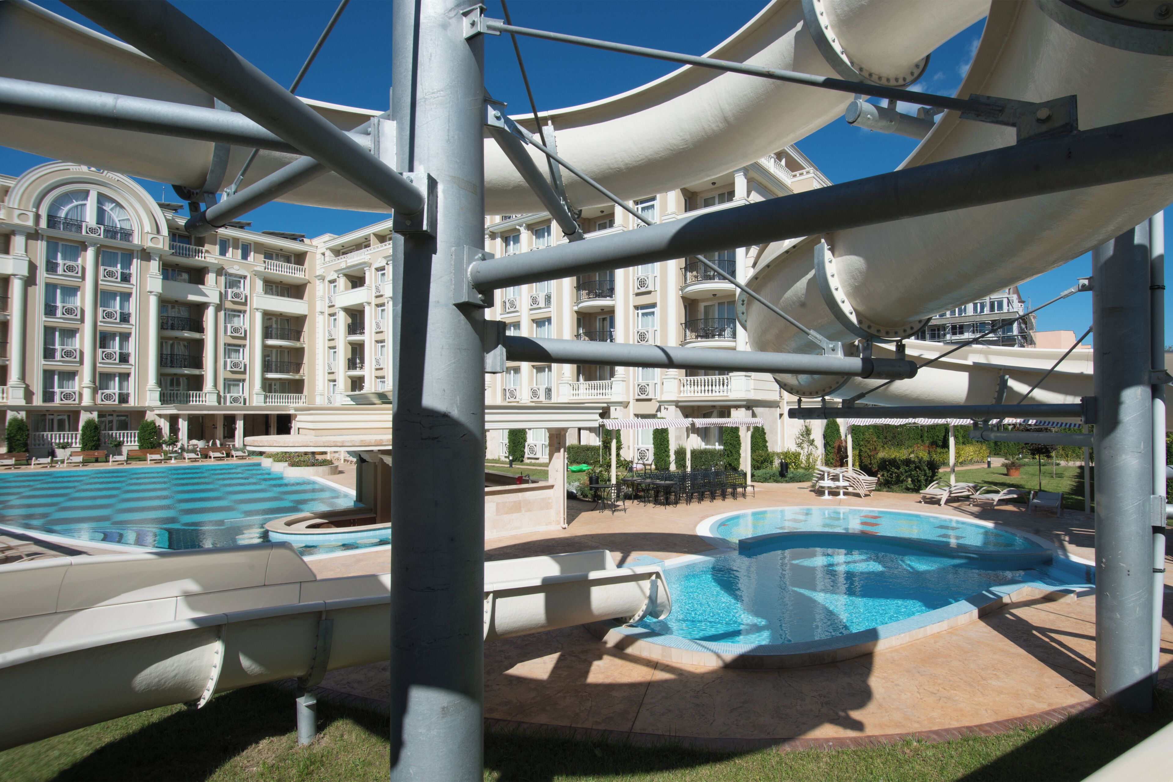 Un hotel con una piscina grande, un tobogán de agua y un edificio de varios pisos con balcones.