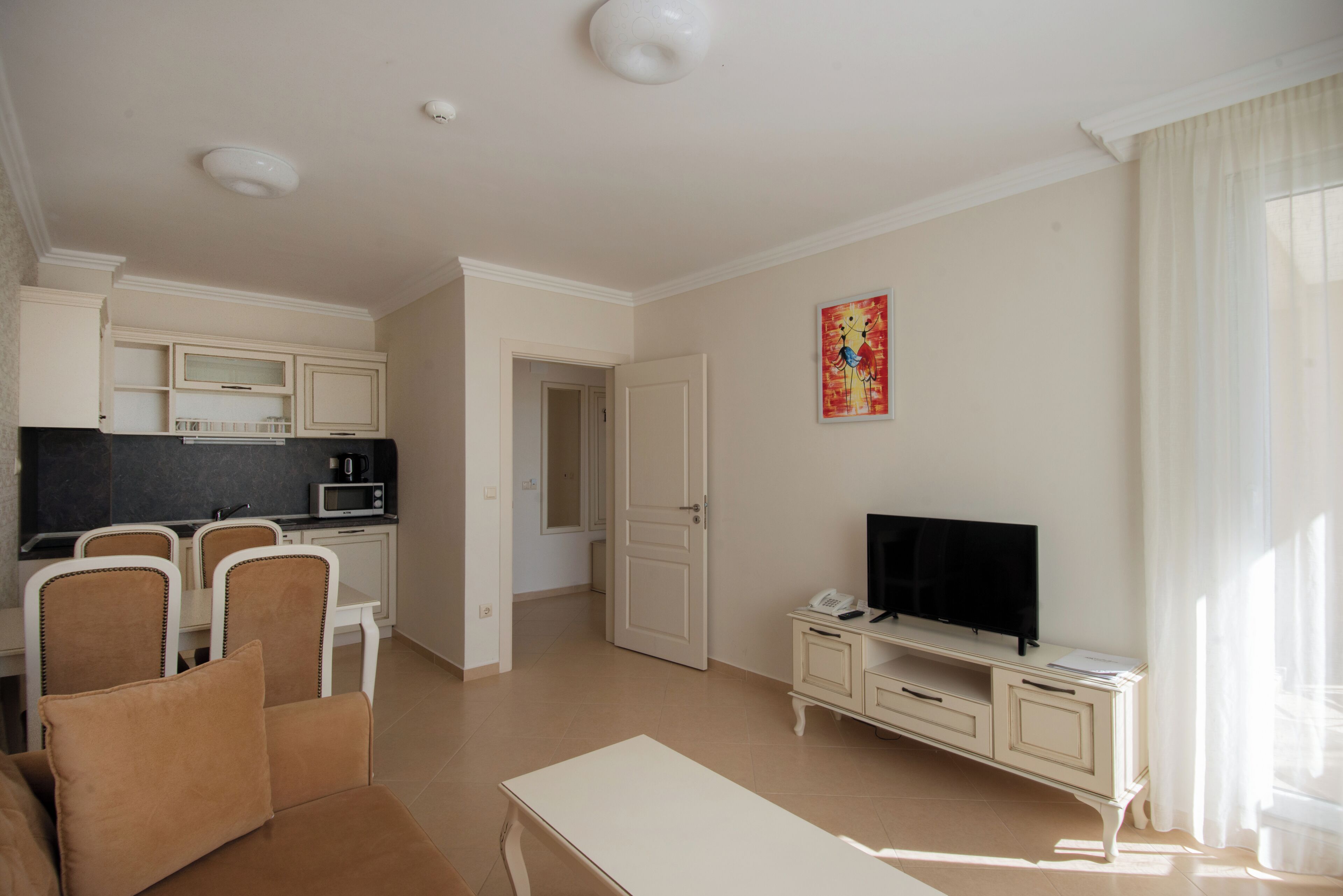A living room with a sofa, TV, and a dining area with chairs and a table.