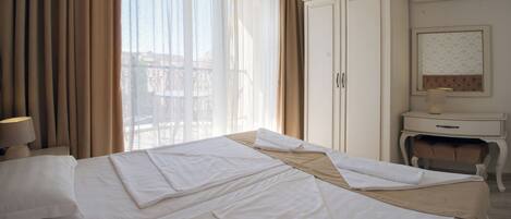 A hotel room with a bed, curtains, a desk, and a chair.