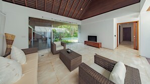 A spacious living area with a high ceiling, a television, and a view of a garden. - Villa SS Chang (Canggu)