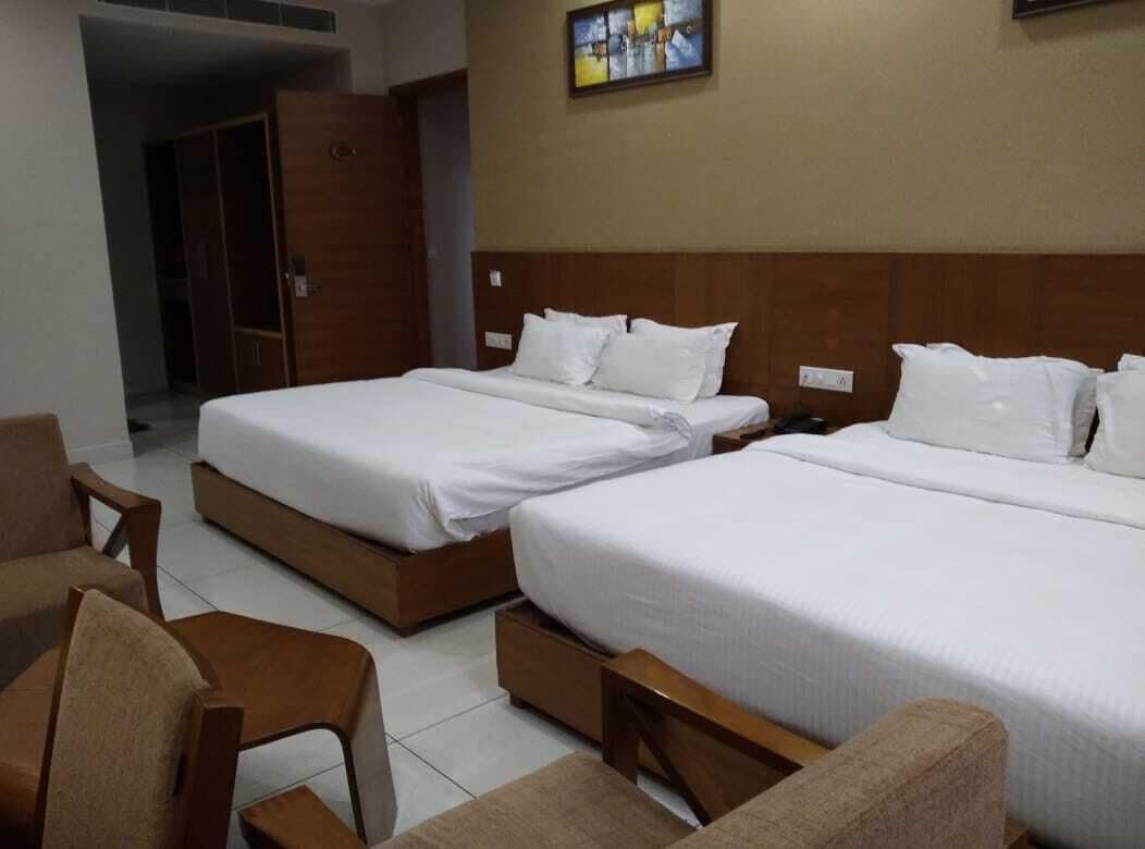 A hotel room with two beds, wooden headboards, and a wardrobe.