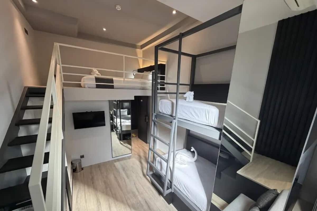 Una habitación de hotel moderna con literas, una escalera y una pequeña zona de estar.
