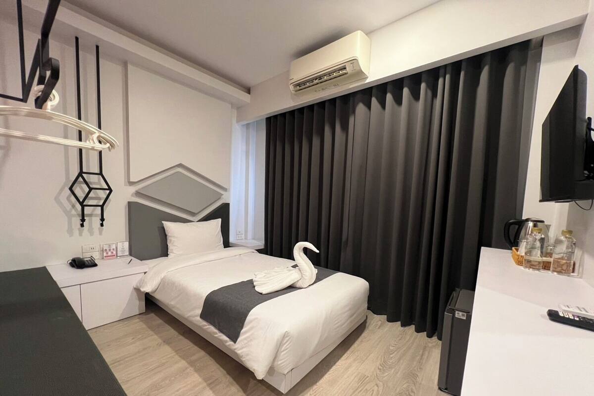 Una habitación de hotel moderna con cama, mesita de noche y televisión.