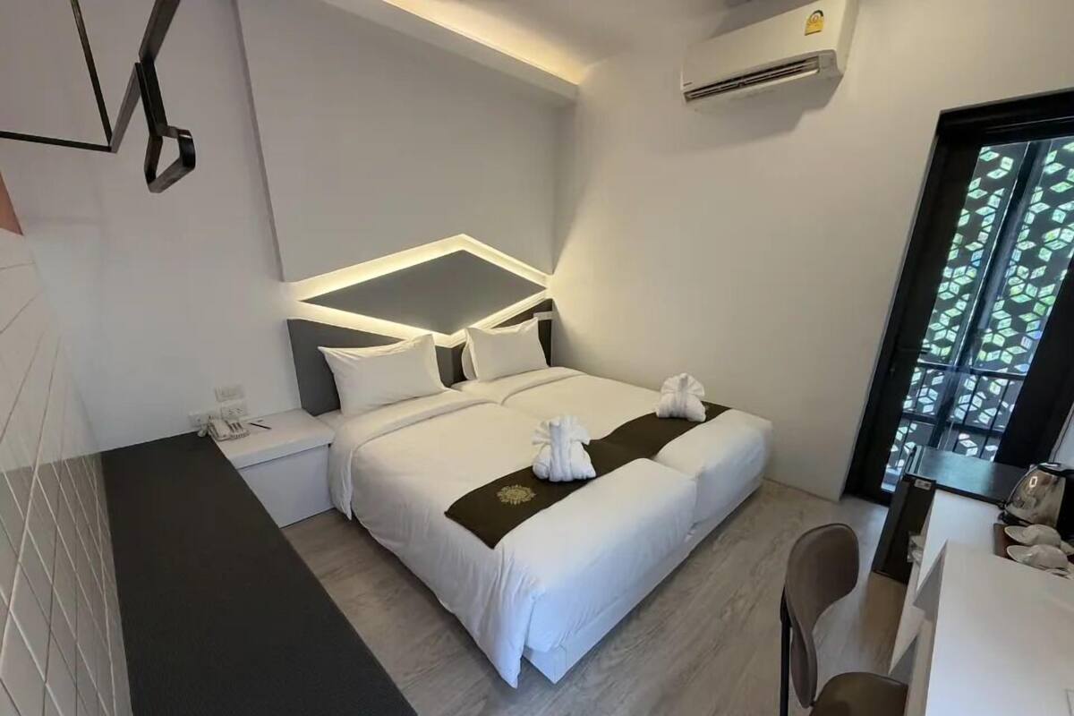 Una habitación de hotel moderna con cama, mesita de noche y escritorio con sillas.