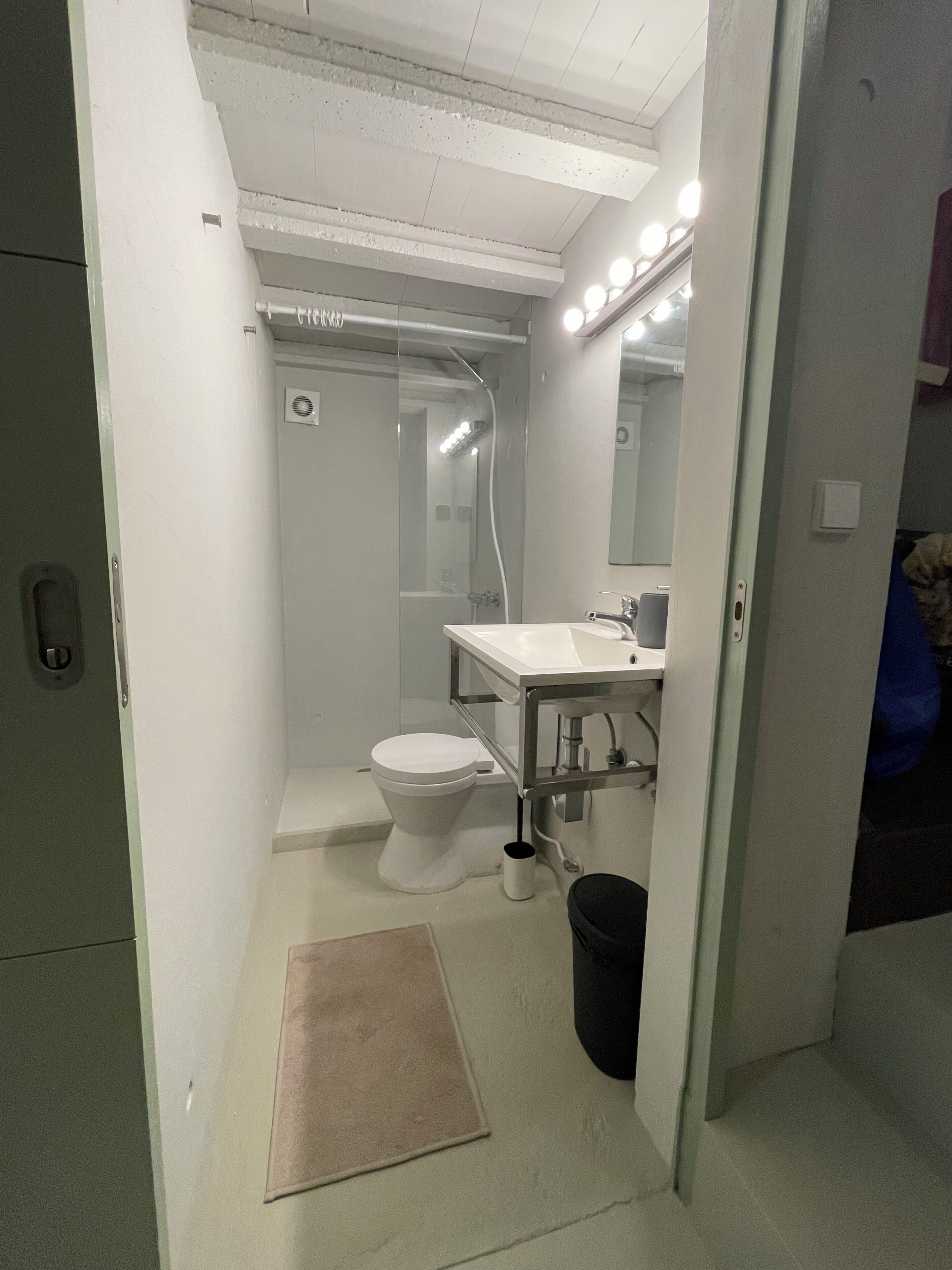 A bathroom with a toilet, sink, mirror, and shower.