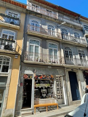 Ein mehrstöckiges Gebäude mit Balkonen, einem Laden Eingang und einer sichtbaren Hausnummer.