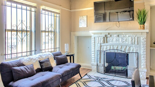 Una sala de estar con chimenea, un sofá y un televisor colocado encima.
