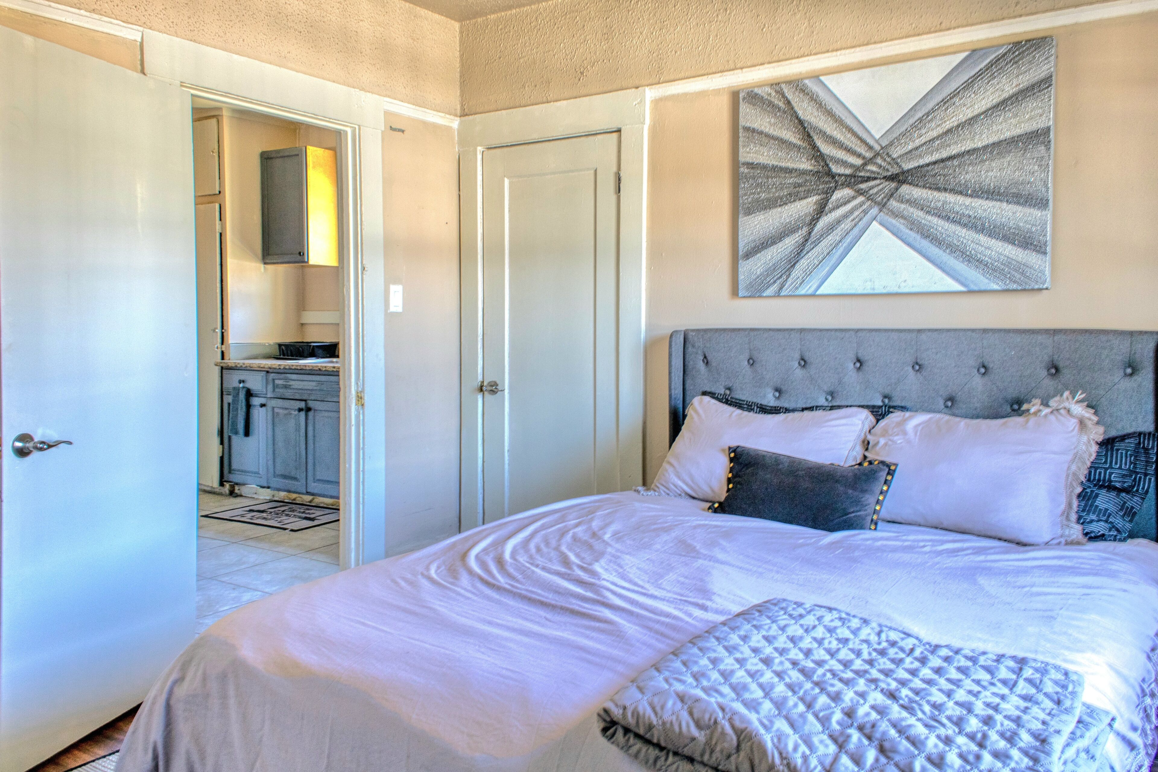 Une chambre à coucher avec un grand lit, une tête de lit et un tableau au mur.