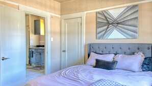 Un dormitorio con una cama grande, un cabecero y un cuadro en la pared.