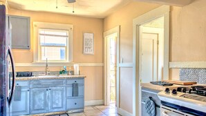 Una cocina con gabinetes grises, estufa, lavabo y ventana.
