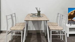 Un comedor con una mesa y sillas, un cuadro en la pared y una pequeña mesa con un cuenco y palillos.