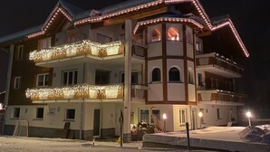 A multi-story hotel with balconies, a central tower, and snow on the ground. - Bedroom Retreat in Saas Valley (Saas Grund)
