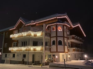Ein mehrstöckiges Hotel mit Balkonen, einem zentralen Turm und Schnee auf dem Boden.