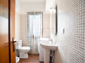 A bathroom with a toilet, sink, and shower curtain. - Apartment in Sardinia Near Stunning Beaches (Golfo Aranci)
