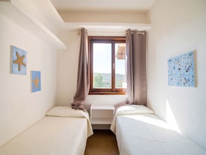 A room with two beds, a window with curtains, and wall art. - Apartment in Sardinia Near Stunning Beaches (Golfo Aranci)