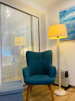 A teal armchair, a standing floor lamp, a radiator, and a window with blinds. - Holiday Home in Porto da Cruz With Garden (Machico)