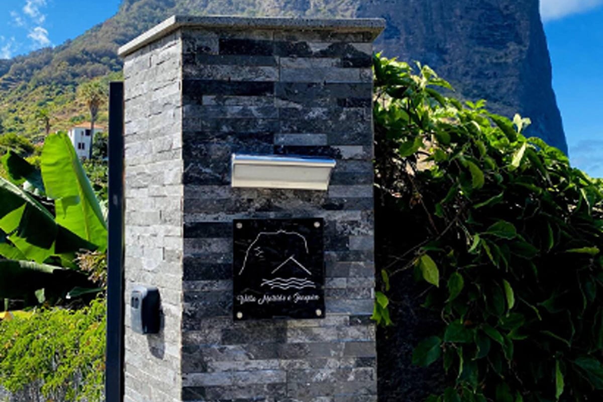 Un pilier de pierre orné d’une plaque, une boîte aux lettres et une vue sur une montagne.