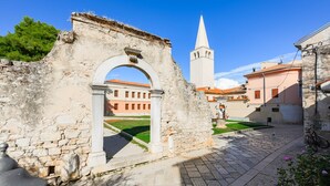 An ancient stone archway leading to a courtyard with a church tower in the background. - Apartment in Porec Near Old Town Beach (Porec)