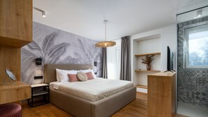A modern bedroom with a large bed, a wooden desk, a TV, and a wall with a leaf pattern. - Apartment in Porec Near Old Town Beach (Porec)