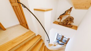 Una scala in legno con corrimano in metallo, una porta in legno e una piccola mensola con una scultura di un cane e un leone.