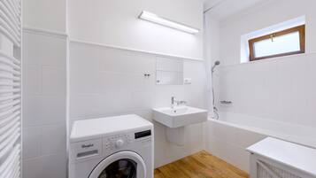 Un baño moderno con lavadora y secadora integradas, un lavamanos y una bañera.
