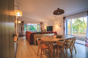 Un interior moderno con una mesa de comedor de madera, sillas, un sofá y un televisor.