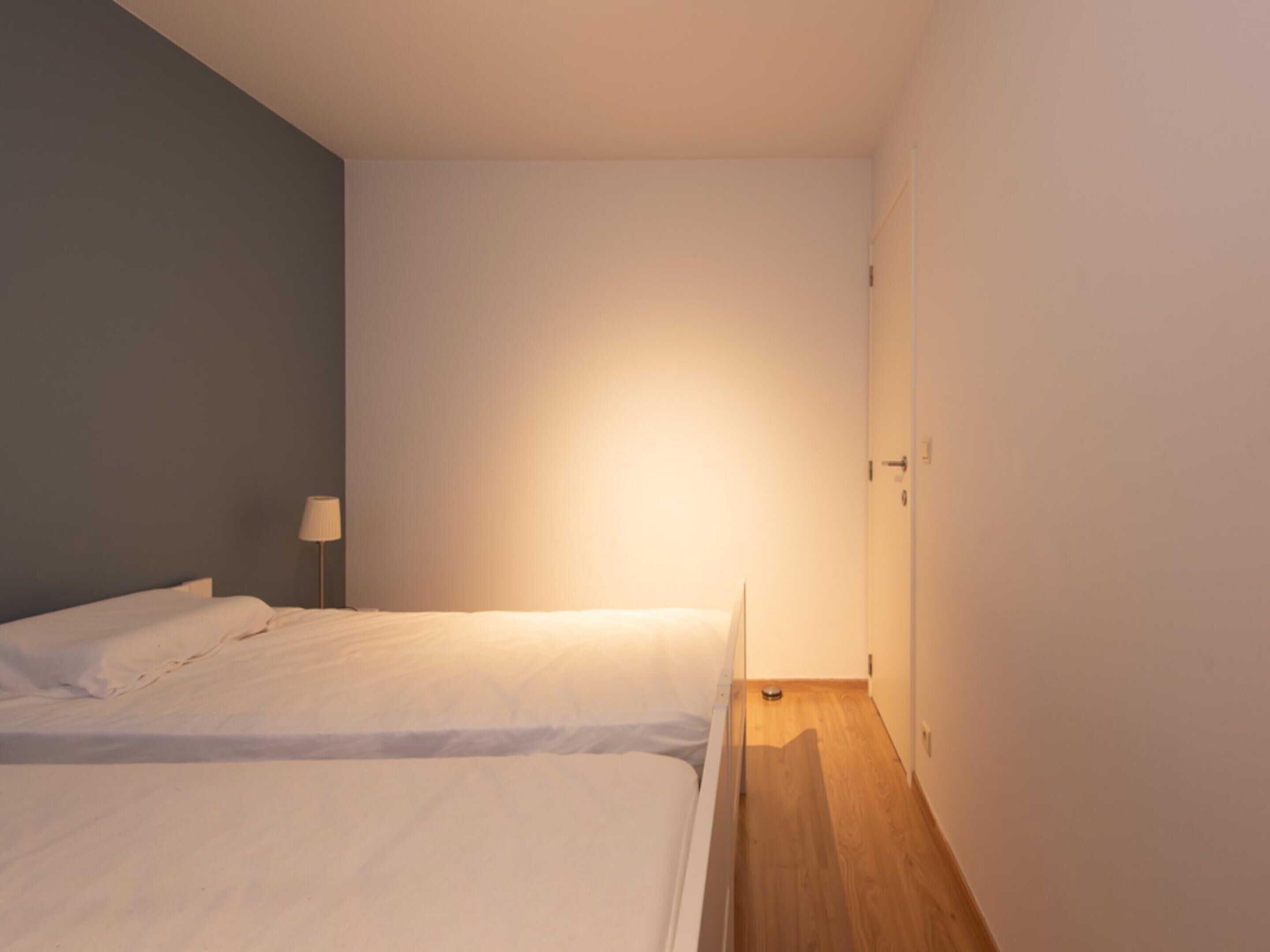 Ein kleines, sauberes Zimmer mit zwei Betten, einem Nachttisch und einer Lampe.
