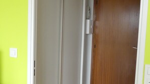 Un pasillo con una puerta de madera, un interruptor de luz y un termostato en la pared.