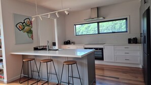 Une cuisine moderne dotée d’un grand îlot central, de tabourets de bar, d’une fenêtre et d’un tableau accroché au mur.