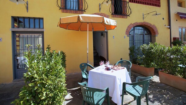 Un área de comedor al aire libre con una mesa, sillas y una sombrilla.