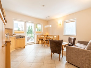 A modern kitchen with wooden cabinets, a dining area with a table and chairs, and a sofa. - Apartment With Terrace in Hollersbach (Hollersbach im Pinzgau)