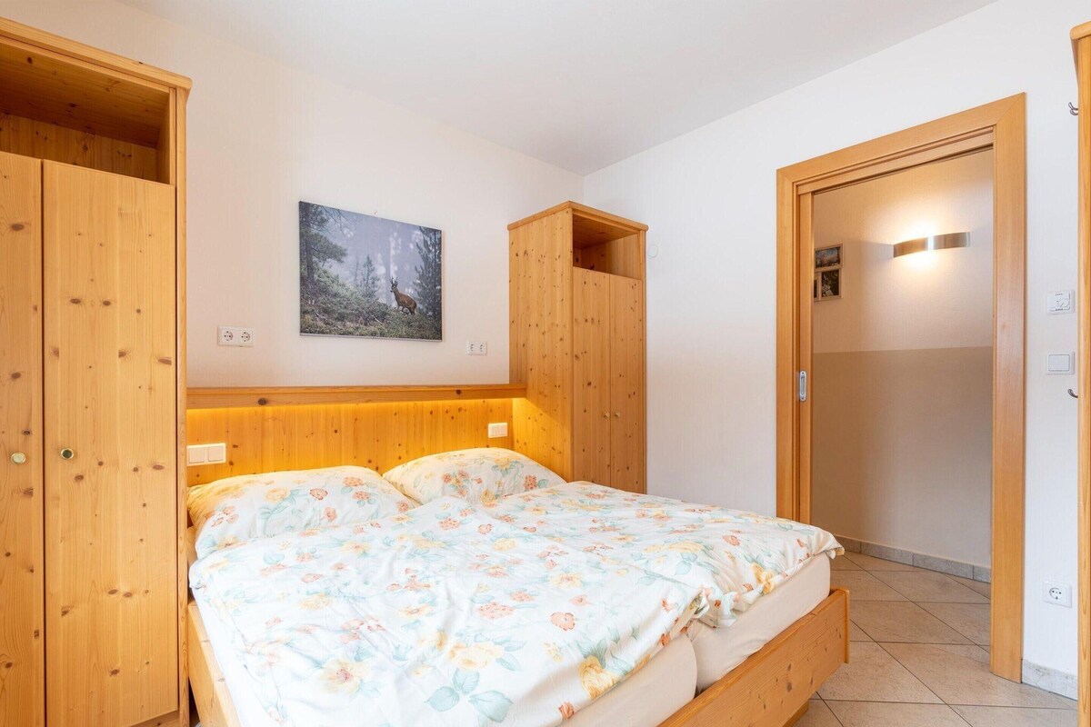 A bedroom with a wooden bed, a nightstand, a wardrobe, and a painting on the wall.