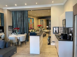 A modern living space with a dining area, a sofa, a coffee table, and a kitchen area with a microwave. - Modern Suite in the Taunus (Bad Camberg)