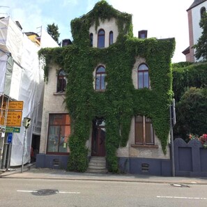 A building covered in ivy with a traditional architectural style, featuring multiple windows and a central entrance. - Modern Suite in the Taunus (Bad Camberg)
