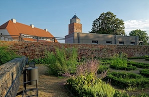 A courtyard with a brick wall, a tower, and a building with a red roof. - Modern Suite in the Taunus (Bad Camberg)