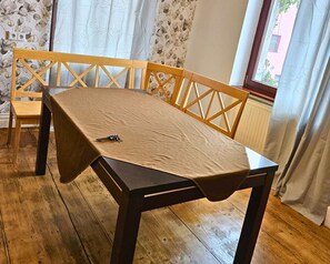 A dining table with a brown tablecloth, a key on it, and a wooden chair with a cross-back design. - Modern Suite in the Taunus (Bad Camberg)